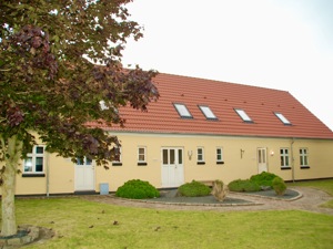 Billede af Basen Fyn på Thulevej i Odense. En gul bygning med rødt tegltag omgivet af en græsplæne og et grønt tag.