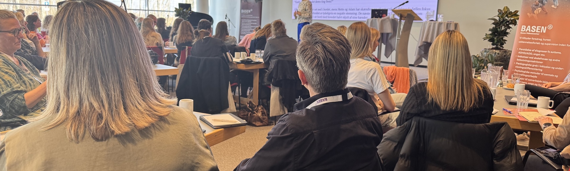 Mennesker samlet i en sal der ser på en der præsenterer