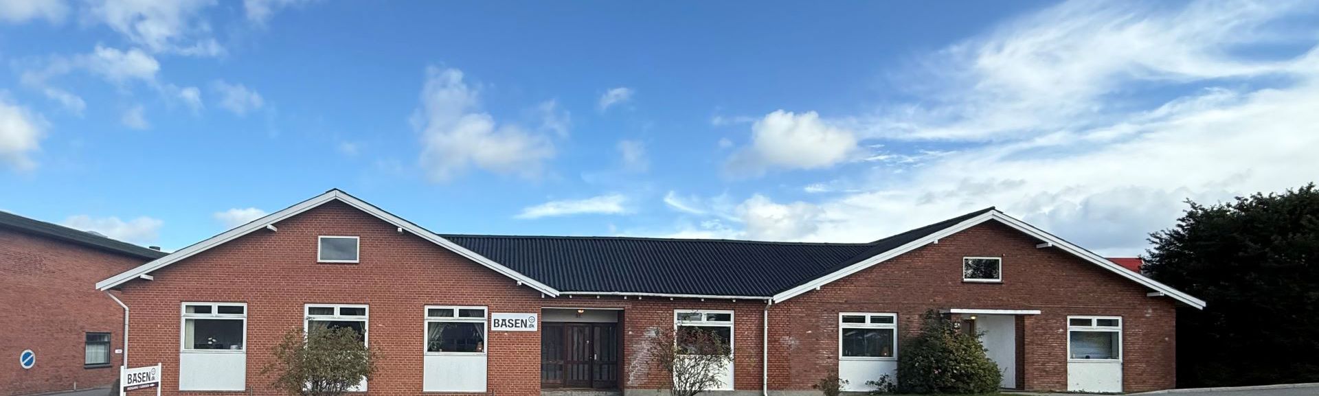 Rød murstensbygning set fra gaden med blå himmel oven over