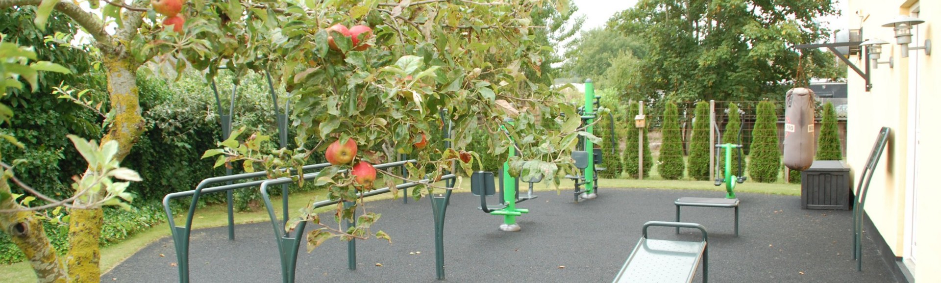 Træningsredskaber placeret udendørs omgivet af frugttræer