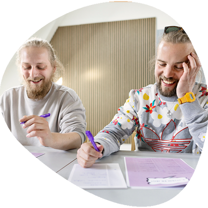 To mænd der sidder og smiler ved et bord.