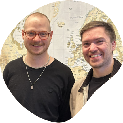 To mænd står sammen og smiler. I baggrunden er der et verdenskort