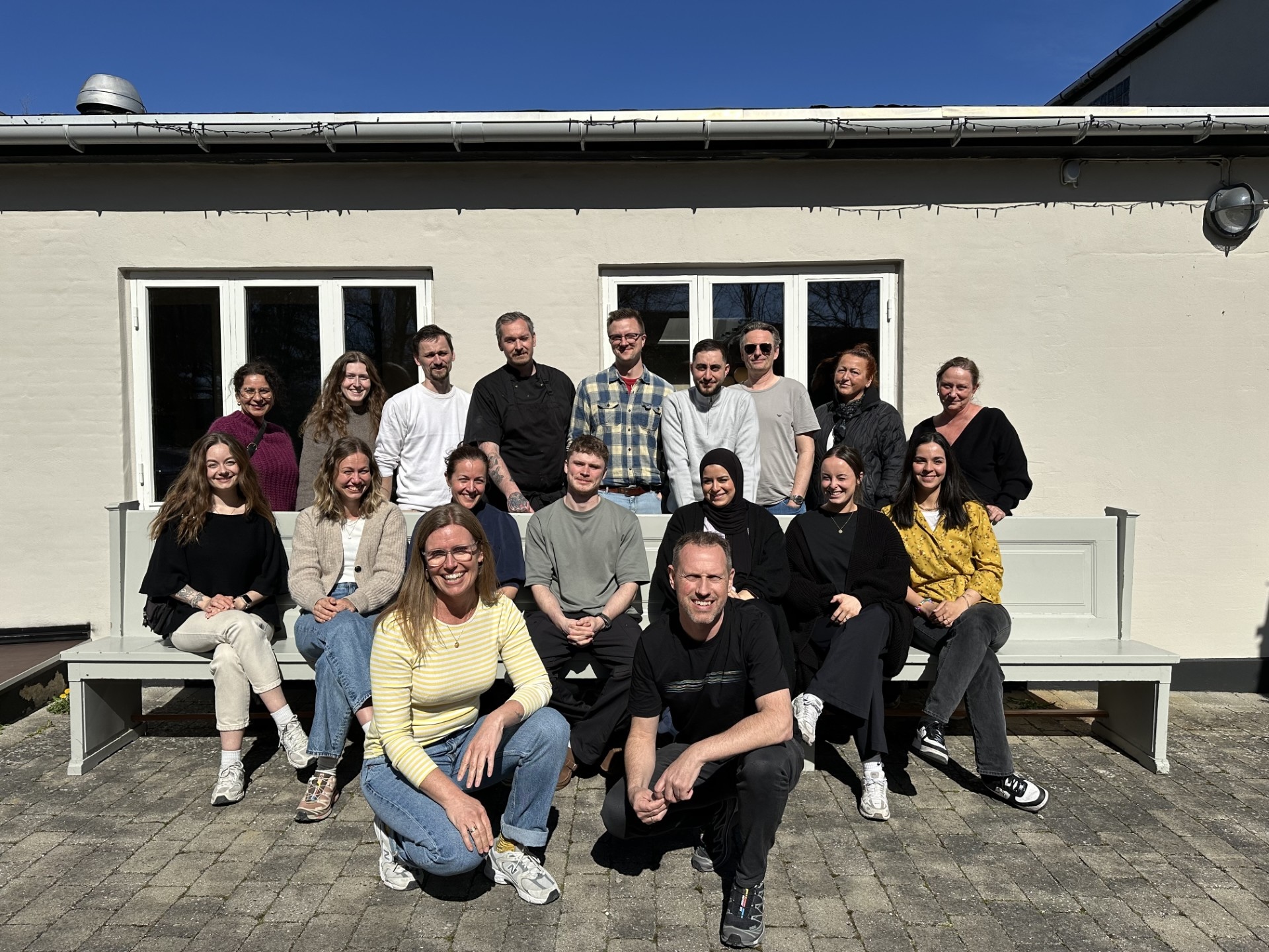 Gruppefoto af alle Basen Vests medarbejdere foran skolen.