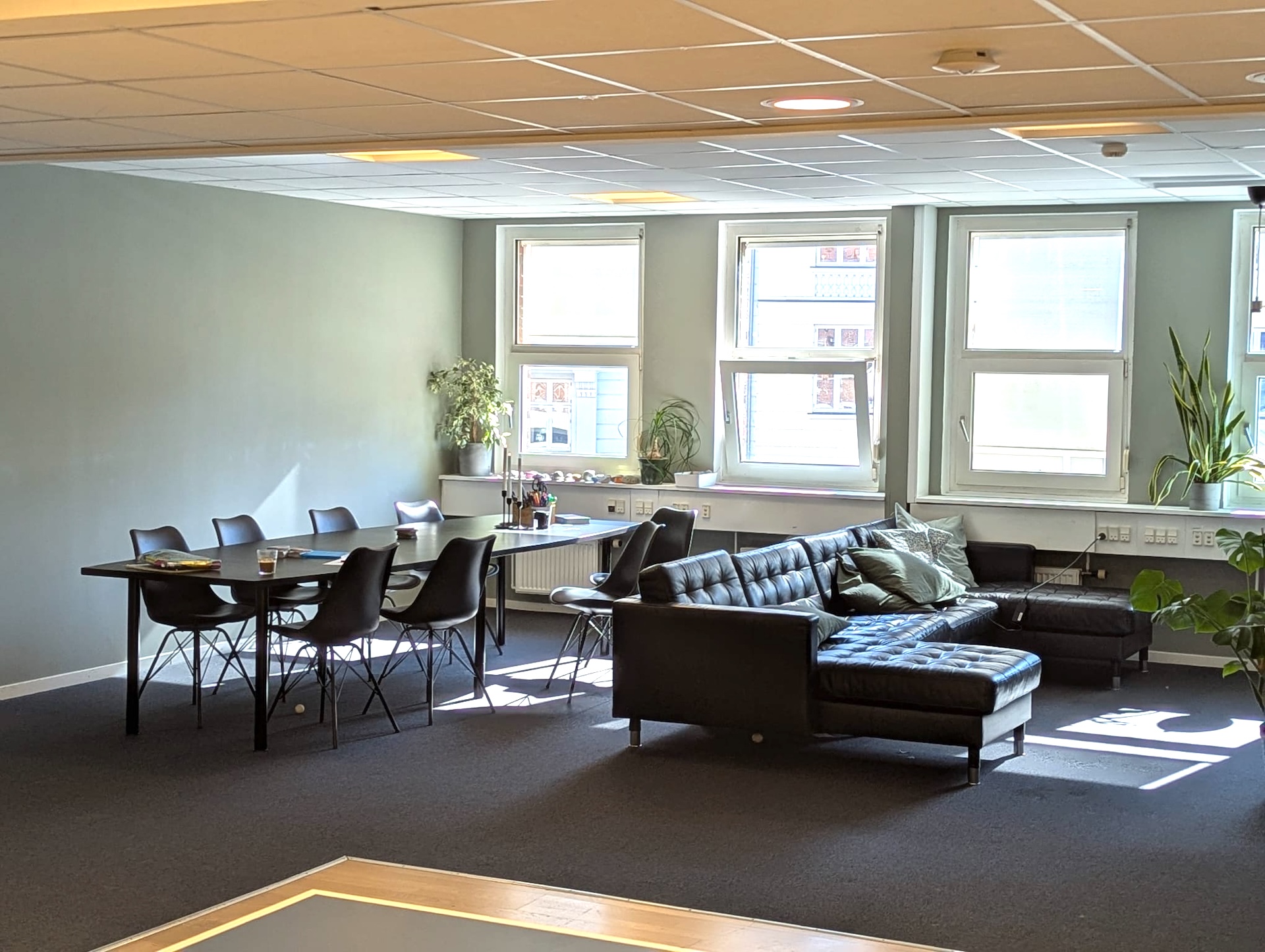 Fællesrum med langbord og stole samt sofaområde på Basen KBH 2.