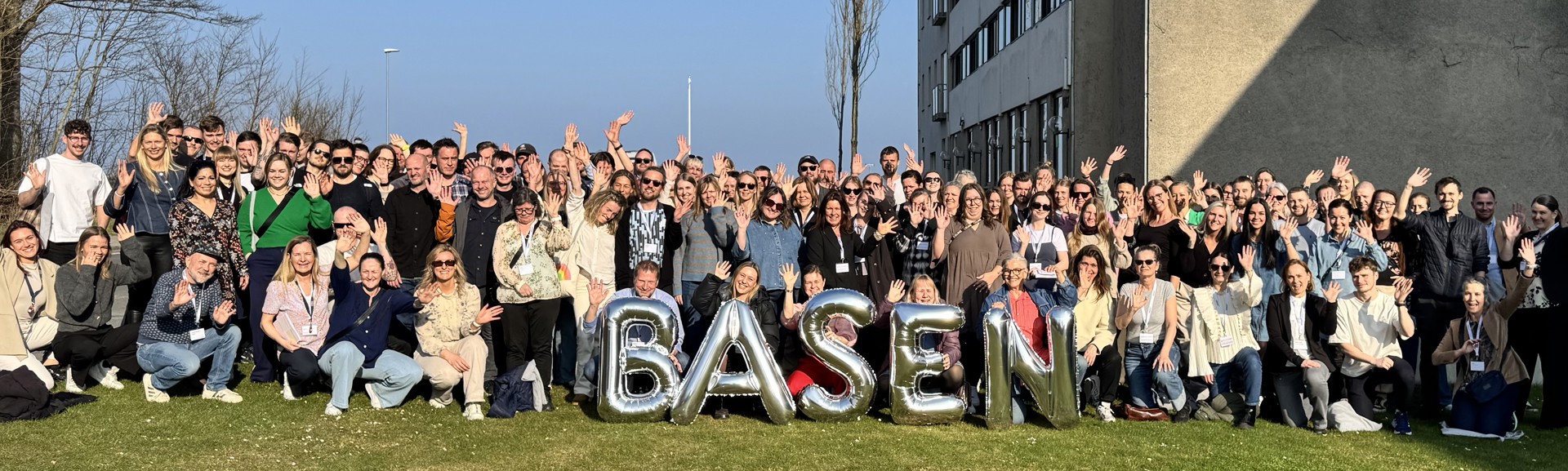 Stort gruppefoto af Basens medarbejdere fra 2025 med bogstavsballoner i forgrunden som udgør ordet; Basen