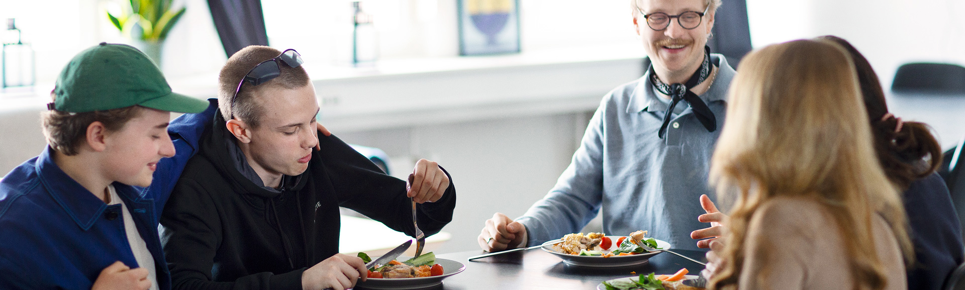 Fem mennesker der spiser frokost sammen