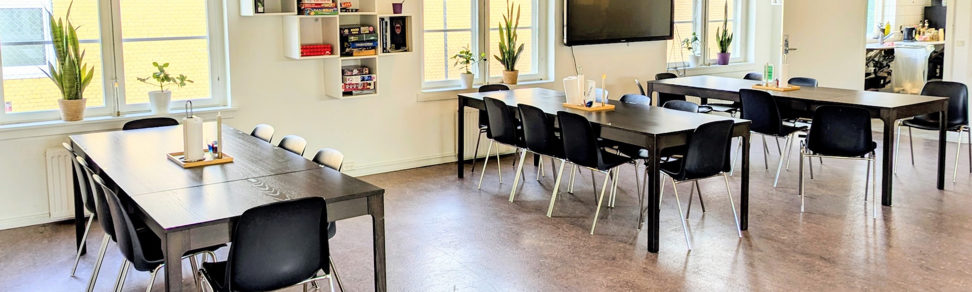 lyst rum med tre borde med stole omkring