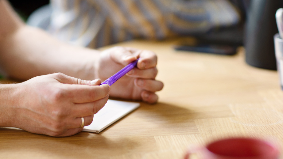en der holder en lille kuglepen i hånden
