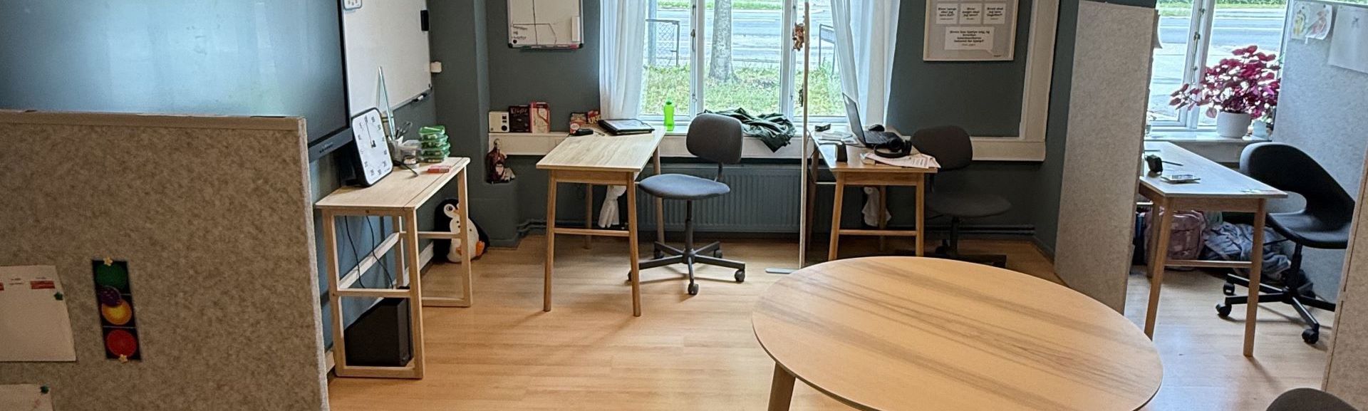 Rum med borde og stole og vinduer i baggrunden